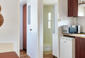 Vue intérieure du Bungalow Essential Golero à TAIGA Delta de l'Ebre, Espagne, montrant cuisine et salle de bain.