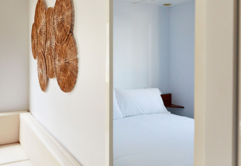 Dormitorio minimalista en Bungalow Essential Golero, TAIGA Delta de l'Ebre, España, con ropa de cama blanca.