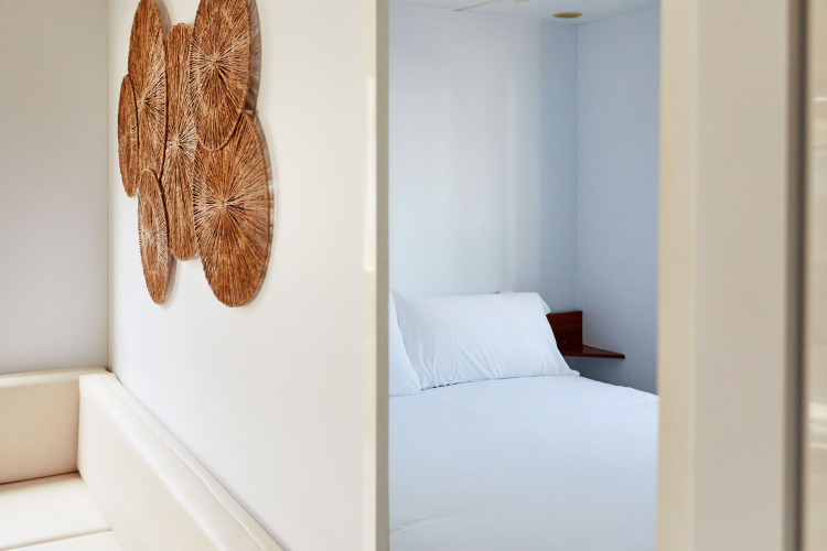 Dormitorio minimalista en Bungalow Essential Golero, TAIGA Delta de l'Ebre, España, con ropa de cama blanca.