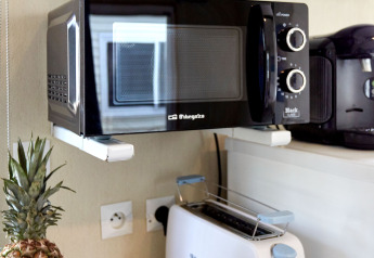 Angolo cucina nel Bungalow Essential Golero con microonde, tostapane e ciotola di frutta a TAIGA Delta de l'Ebre.