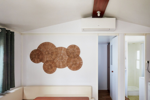 Wohnbereich im Bungalow Essential Golero bei TAIGA Delta de l'Ebre, Spanien, mit Wandkunst und Klimaanlage.