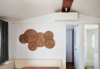 Sala de estar en Bungalow Essential Golero en TAIGA Delta de l'Ebre, España, con arte mural y aire acondicionado.