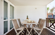 Terraza exterior de madera en Bungalow Confort Delta con mesa, sillas y piña como centro de mesa.