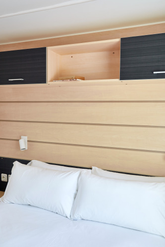 Foto interior de Bungalow Confort Delta con paneles de madera, almohadas blancas y armarios abiertos.