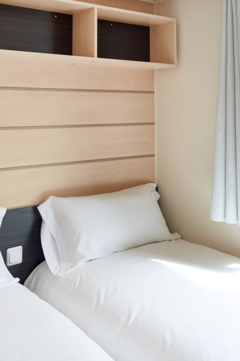 Due letti singoli con lenzuola bianche in una luminosa cabina del Bungalow Confort Delta, TAIGA Delta de l'Ebre, Spagna.