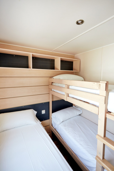 Bright room with bunk bed and single bed at Bungalow Confort Delta, TAIGA Delta de l'Ebre, Spain.