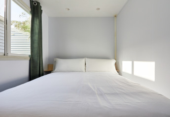 Minimalistisk soveværelse i Bungalow Essential Flamenc på TAIGA Delta de l'Ebre med stor seng og vindue.