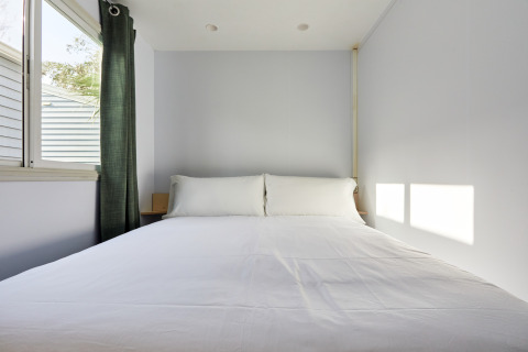 Modernes Schlafzimmer im Bungalow Essential Flamenc bei TAIGA Delta de l'Ebre mit Bett und großem Fenster.