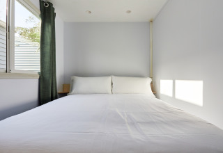 Chambre minimaliste du Bungalow Essential Flamenc à TAIGA Delta de l'Ebre avec lit et fenêtre lumineuse.