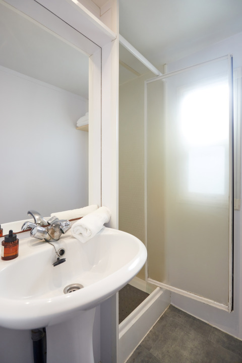 Pequeño baño con lavabo, espejo y ducha en Bungalow Essential Flamenc, TAIGA Delta de l'Ebre, España.