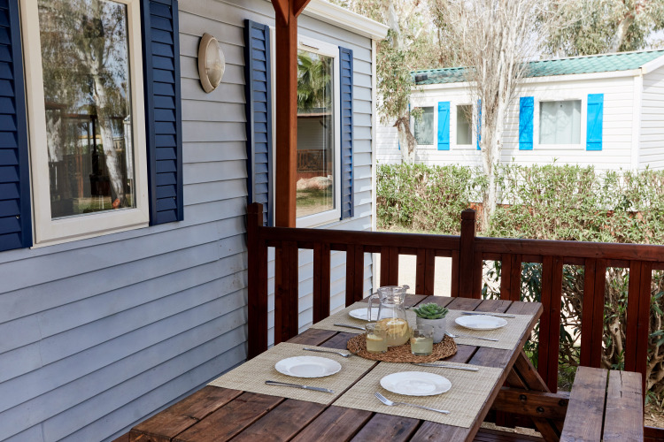 Buiten eettafel op de veranda van Bungalow Confort Daurada bij TAIGA Delta de l'Ebre in Spanje, gedekt voor vier.