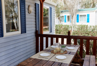 Buiten eettafel op de veranda van Bungalow Confort Daurada bij TAIGA Delta de l'Ebre in Spanje, gedekt voor vier.