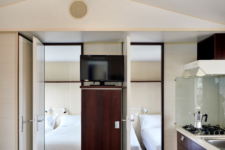 Interieur van Bungalow Confort Daurada bij TAIGA Delta de l'Ebre, Spanje, met slaapkamers en keuken.