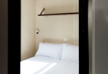 Habitación pequeña con cama doble, estante y lámpara en Bungalow Confort Daurada, TAIGA Delta de l'Ebre, España.