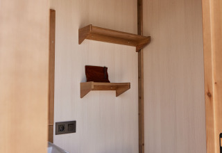 Badkamer met toilet, wastafel en houten rekjes in de Glamping Cabin-Tent Senyoret bij TAIGA Delta de l'Ebre, Spanje.