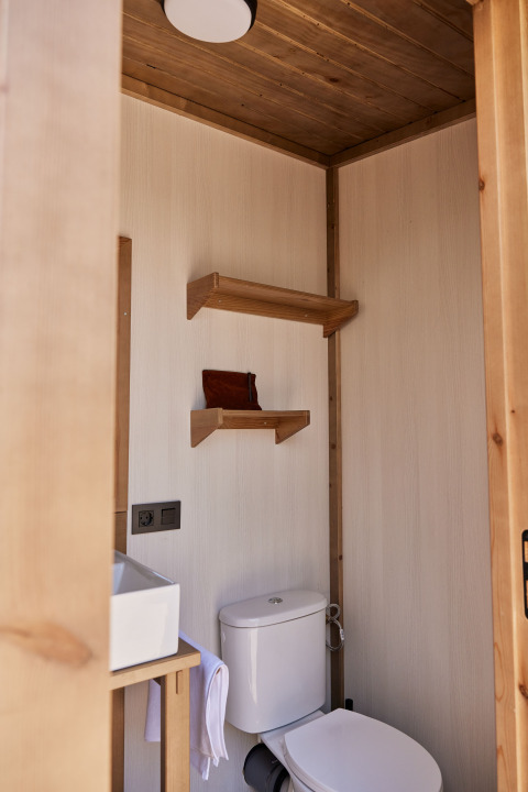 Bagno con WC, lavandino e mensole in legno nella Glamping Cabin-Tent Senyoret, TAIGA Delta de l'Ebre, Spagna.