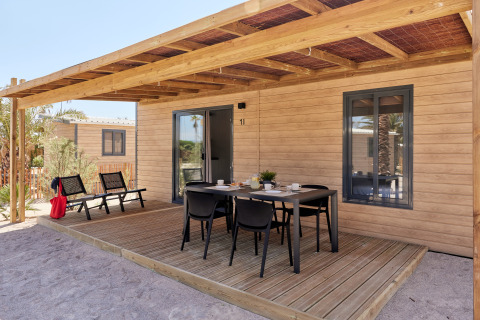 Terraza exterior del Bungalow Premium Gregal con mesa de comedor y sillas bajo una pérgola de madera.
