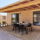 Udendørs terrasse af Bungalow Premium Gregal med spisebord og stole under en træ-pergola.