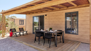 Terraza exterior del Bungalow Premium Gregal con mesa de comedor y sillas bajo una pérgola de madera.