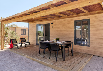 Terraza exterior del Bungalow Premium Gregal con mesa de comedor y sillas bajo una pérgola de madera.