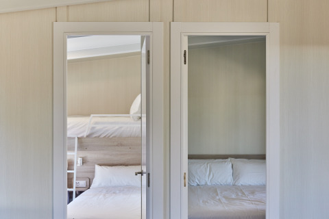 Dos habitaciones en Bungalow Premium Gregal en TAIGA Delta de l'Ebre, España, con cama doble y litera.