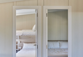 Twee slaapkamers in Bungalow Premium Gregal bij TAIGA Delta de l'Ebre, Spanje, met dubbelbed en stapelbed.