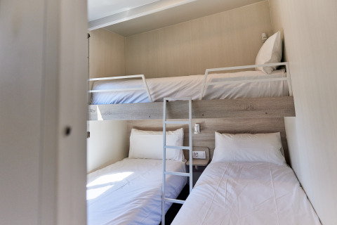 Zimmer im Bungalow Premium Gregal mit Etagenbett und zwei Einzelbetten auf TAIGA Delta de l'Ebre, Spanien.