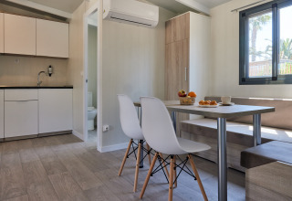 Alojamiento glamping moderno con cocina americana, zona de comedor y gran ventana con vistas naturales.