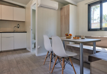Alojamiento glamping moderno con cocina americana, zona de comedor y gran ventana con vistas naturales.