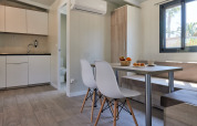 Moderne glampingaccommodatie met kitchenette, eethoek en ruim raam met zicht op de natuur.