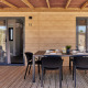 Terrasse einer Glamping-Unterkunft mit Holzwand, Tisch, vier Stühlen und Gedeck unter einem Holzdach.