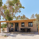 Træhytte ved navn Bungalow Premium Ebre med terrasse, udendørs siddepladser og omgivet af træer.
