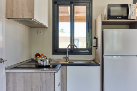 Modern kitchen in Bungalow Premium Ebre at TAIGA Delta de l'Ebre, Spain, with window, stove, and fridge.