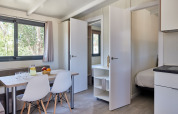 Interior luminoso del Bungalow Premium Ebre con mesa de comedor, sillas y vista al dormitorio en España.