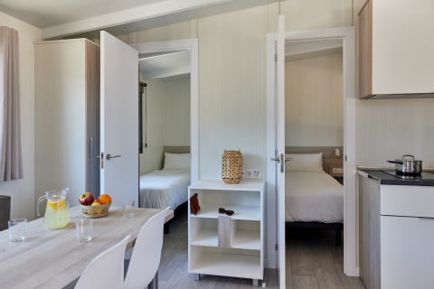 Interior view of Bungalow Premium Ebre at TAIGA Delta de l'Ebre, Spain, showing two bedrooms, kitchen and dining table.