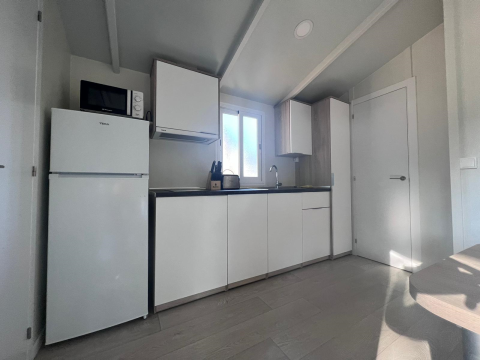 Moderne køkken i Bungalow Confort Poniente ved TAIGA Conil i Spanien, med hvide skabe og naturligt lys.