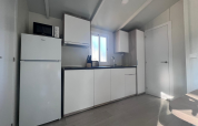 Moderne køkken i Bungalow Confort Poniente ved TAIGA Conil i Spanien, med hvide skabe og naturligt lys.
