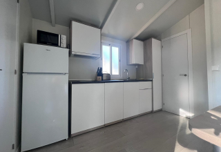 Moderne køkken i Bungalow Confort Poniente ved TAIGA Conil i Spanien, med hvide skabe og naturligt lys.