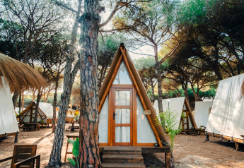 Knus Glamping Tipi Pinar chalet in het bos, omringd door bomen en soortgelijke tenthuisjes.