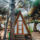 A cozy Glamping Tipi Pinar chalet in the woods, surrounded by trees and similar tent-like cabins.