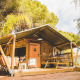 Safari teltet Glamping Safari Mistral med træveranda og picnicbord i et naturområde omgivet af træer.