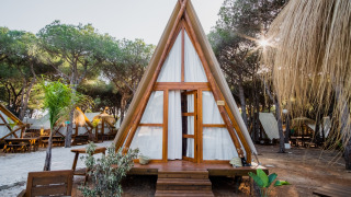 Glamping Tipi Almadraba, ein modernes Tipi-Zelt im Wald mit Vorhängen und Holzmöbeln im Freien.