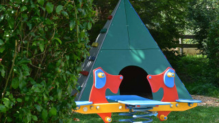 Parque infantil en Drau Camping Sachsenburg, Carintia, con balancín colorido y tipi verde para niños.