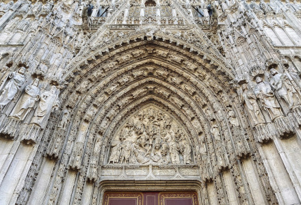 Entrée de cathédrale gothique ornée de statues finement sculptées, probablement en Normandie, France.