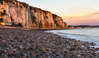 Paysage côtier près de Quiberville en Normandie, France, avec des falaises blanches et une plage de galets au crépuscule.