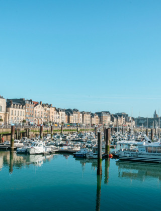 Port près de Quiberville en Normandie, France, avec des bateaux amarrés et des façades colorées en arrière-plan.