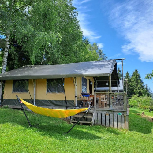 Safari-Zelt Base Lodge auf Camping Les Sapins in Frankreich mit gelber Hängematte und grünem Rasen.