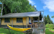 Safari tent Base Lodge at Camping Les Sapins in France, with a yellow hammock and lush green scenery.