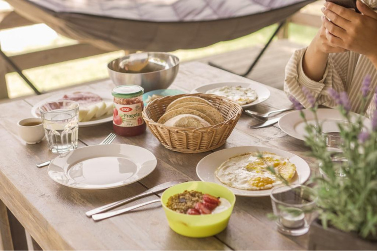 Frühstückstisch mit Brot, Eiern und Marmelade im Base Lodge Safari-Zelt, Camping Les Sapins, Frankreich.