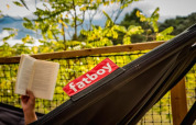 Iemand leest een boek in een Fatboy-hangmat bij het safaritent Base Lodge, Camping Les Sapins, Frankrijk.